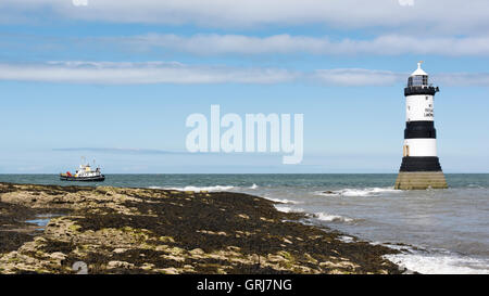 Trwyn Du Leuchtturm und ein Boot vom Felsen am Schwarzpunkt, Penmon, Anglesey, Wales, UK Stockfoto