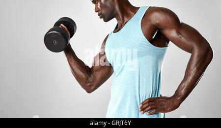 Gemischte Rassen Mann Training mit Hanteln vor grauem Hintergrund. Junge fit Mann eine Hantel heben. Stockfoto