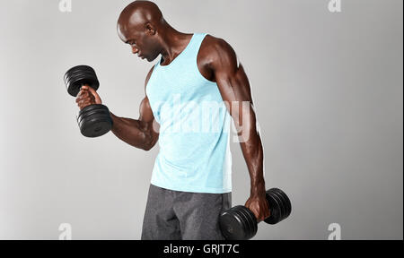 Schuss von jungen muskulösen Mann schwere Hantel Übung für Bizeps. Workout mit Hanteln auf grauen Ba afrikanischen Fitness-Modell Stockfoto