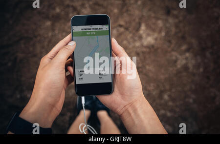 Schuss von weiblichen überprüfen die Zusammenfassung von ihrem Lauf auf Handy hautnah. Frau-Läufer mit einer Fitness-app auf ihr Smartphone. POV Stockfoto