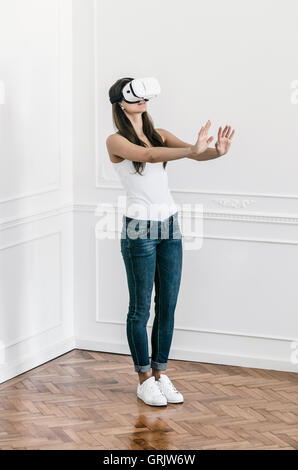 Eine junge Frau steht in einer Wohnung Gefühl in sich selbst trägt eine virtual-Reality-Kopfhörer Stockfoto