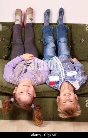 kleine Mädchen und Jungen auf dem Kopf stehend auf dem Bett liegend Stockfoto