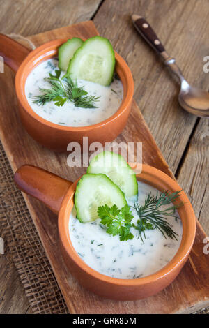 Tarator, kalte Suppe mit Gurken, Joghurt und frischen Kräutern auf Holztisch Stockfoto