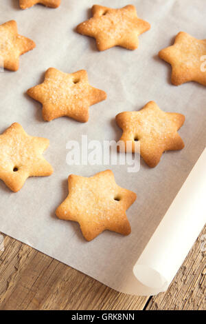 Hausgemachter Lebkuchen (Sterne) auf Backblech, Papier und rustikalen Holztisch Stockfoto