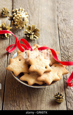 Weihnachten Lebkuchen auf rustikalen Holztisch mit goldenen Tannenzapfen und rotes Band für Winterurlaub Stockfoto