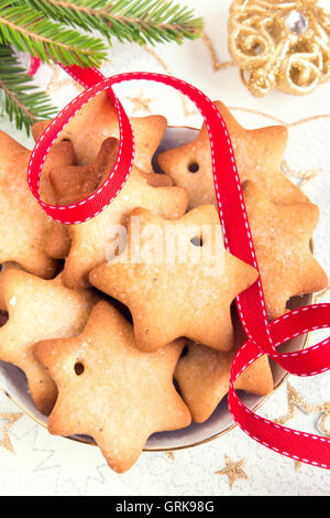 Weihnachten Lebkuchen auf weiße Serviette mit goldenen Ornamenten, Tannenzweigen und rotes Band für Winterurlaub Stockfoto