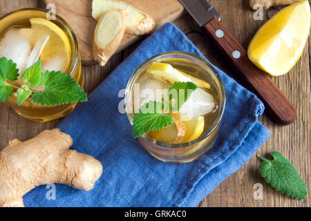 Ginger Ale Soda mit Zitrone, Minze, Ingwer und Eis über rustikale Holz Hintergrund Stockfoto