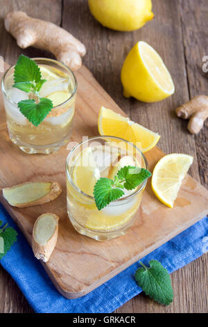 Ginger Ale Soda mit Zitrone, Minze, Ingwer und Eis über rustikale Holz Hintergrund Stockfoto