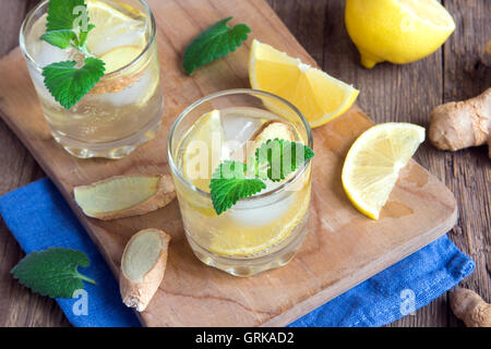 Ginger Ale Soda mit Zitrone, Minze, Ingwer und Eis über rustikale Holz Hintergrund Stockfoto