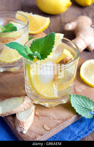 Ginger Ale Soda mit Zitrone, Minze, Ingwer und Eis über rustikale Holz Hintergrund Stockfoto