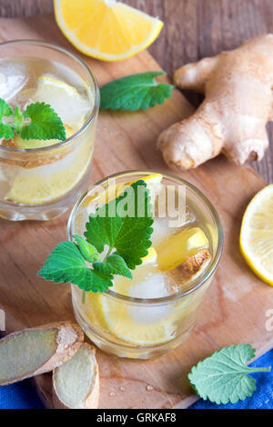 Ginger Ale Soda mit Zitrone, Minze, Ingwer und Eis über rustikale Holz Hintergrund Stockfoto