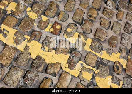 doppelte gelbe Linien auf Kopfsteinpflaster Stockfoto