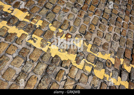 doppelte gelbe Linien auf Kopfsteinpflaster Stockfoto