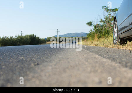 Auto an der Seite einer Straße in ländlich geprägtes Land. Hinterhalt mit dem schwarzen Auto auf einer asphaltierten Straße. Blick auf ein entgegenkommendes Fahrzeug. Stockfoto