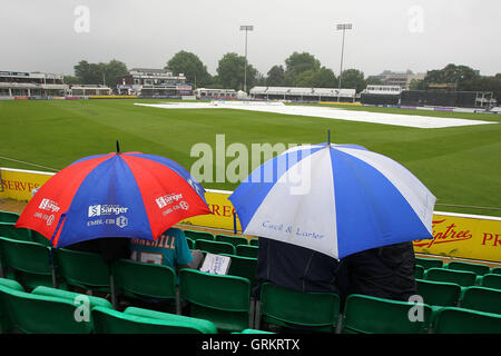 Zuschauern Unterschlupf unter Sonnenschirmen wie Verzögerungen spielen wieder - Essex Adler Vs Gloucestershire CCC - Royal London-ein-Tages-Cup an der Essex County Ground, Chelmsford, Essex - 08.08.14 Regen Stockfoto