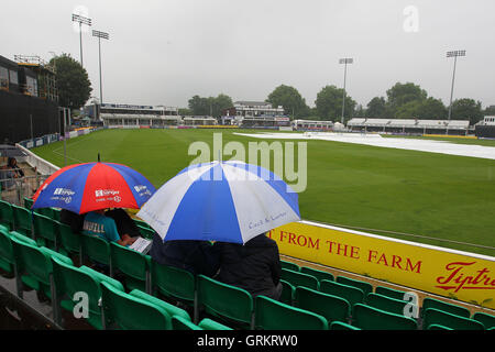 Zuschauern Unterschlupf unter Sonnenschirmen wie Verzögerungen spielen wieder - Essex Adler Vs Gloucestershire CCC - Royal London-ein-Tages-Cup an der Essex County Ground, Chelmsford, Essex - 08.08.14 Regen Stockfoto