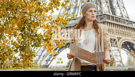 Herbst Kurzurlaube in Paris. In voller Länge Portrait von junge elegante Frau am Ufer in der Nähe von Eiffelturm in Paris, Frankreich mit Karte Stockfoto