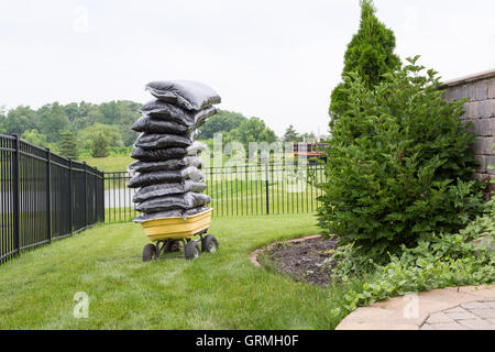 Rindenmulch in Säcken gestapelt auf einem Wagen im Garten taumelt bedenklich, während sie darauf warten auf die Blumenbeete in einem Caref verteilt werden hohe Stockfoto