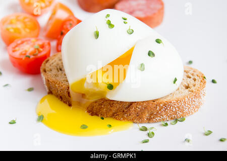 Pochiertes Ei auf Stück Vollkornbrot mit Gemüse und Kräutern hautnah Stockfoto