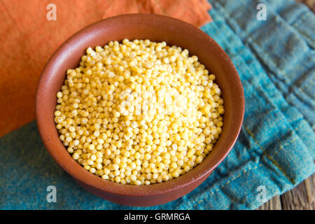 Bio Hirse in Keramikschale auf rustikalen Holztisch hautnah Stockfoto