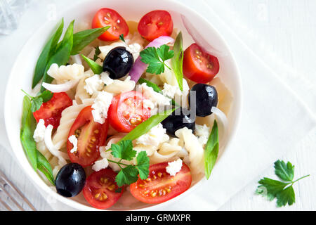 Nudelsalat mit Gemüse, Oliven und Feta auf weißem Hintergrund Stockfoto
