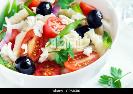 Nudelsalat mit Gemüse, Oliven und Feta auf weißem Hintergrund Stockfoto