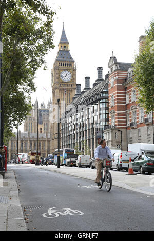 Ein Radfahrer auf einem gemieteten "Boris" Fahrrad nutzt Londons neue Radweg am Victoria Embankment. Big Ben zeigt im Hintergrund. Stockfoto