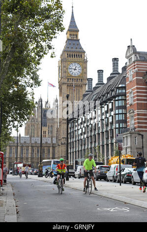 Radfahrer nutzen Londons neuen, getrennten Radweg am Victoria Embankment. Big Ben zeigt im Hintergrund. Stockfoto