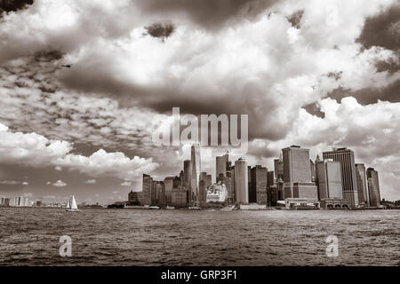 Im Hafen von New York mit dem Bürogebäude von lower Manhattan im Hintergrund ist ein kleines Segelboot Kreuzfahrt. Stockfoto