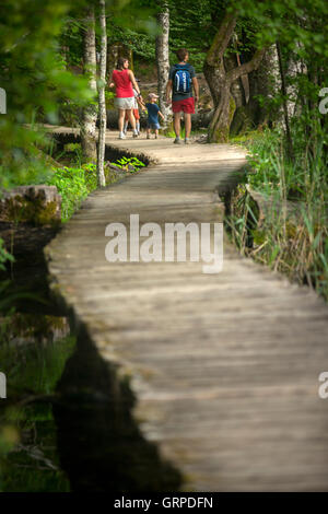 Eine touristische Familie Bummeln auf einem hölzernen Steg (Nationalpark Plitvicer Seen - Kroatien). Urlauber auf einem Holzsteg. Stockfoto