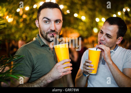 Zwei junge fröhliche männliche Freunde auf Straße oder Park Party im freien Stockfoto