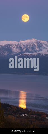 Ein blasser gelber Mond steigt über die Bucht von Alaska. Stockfoto