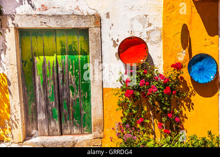 Weiße gelbe Wand grüne Tür Schalen-blau rote Rosen Straße 11. Jahrhundert mittelalterliche Stadt Óbidos Portugal. Stockfoto