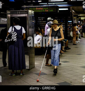 Eine sehbehinderte Frau geht entlang einer u-Bahn-Plattform in New York Stockfoto