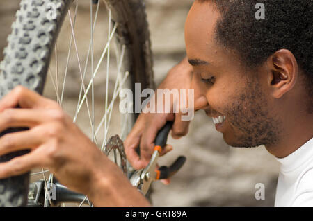 Mann trägt weißes Hemd glücklich arbeiten auf Fahrradmonteure/Fahrradmonteurinnen mit Schraubendreher Werkzeug zu reparieren Stockfoto