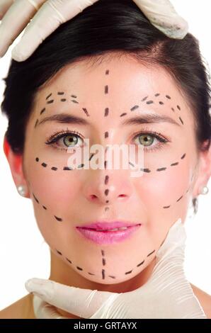 Kopfschuss kaukasischen Frau mit gepunkteten Linien rund um Blick in Kamera, Ärzte Hände halten ihren Kopf, Gesicht Schönheitschirurgie vorbereiten Stockfoto