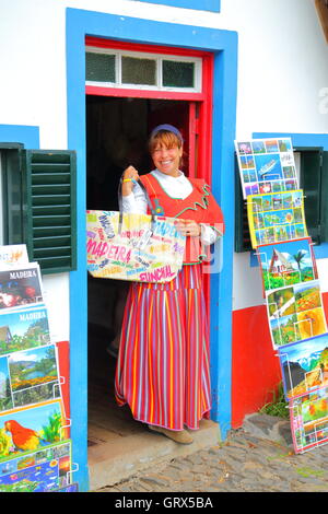 Junge Frau aus Madeira in traditioneller Tracht mit Souvenirs in der Stadt von Santana Stockfoto