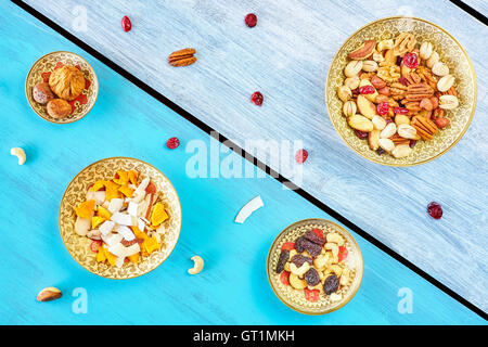 Nüssen und getrockneten Früchten mischen in Schalen auf einem rustikalen Holztisch, Ansicht von oben. Stockfoto