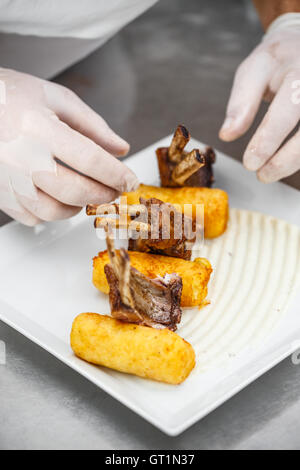 Gebratene Lammkoteletts garniert mit gestampften Kartoffeln gefüllte Kroketten Stockfoto