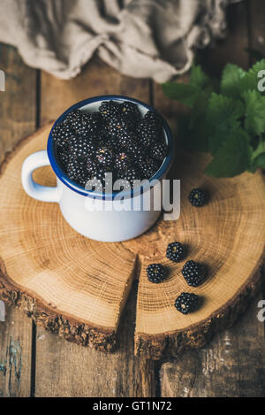 Frischer Garten Brombeeren in weiße Tasse auf die Runde Betreuung aus Holz Stockfoto