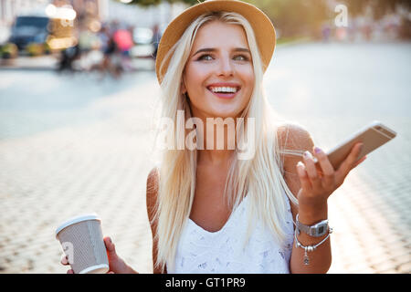 Nahaufnahme Portrait eines Mädchens in Hut Holding take away Kaffeetasse und smartphone Stockfoto