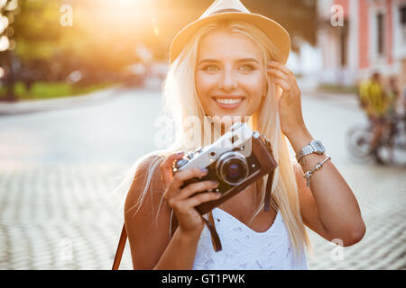 Porträt eines lächelnden blonden Mädchens Retro-Kamera im Freien halten, Nahaufnahme Stockfoto