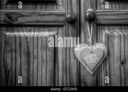 Liebe das Leben Herz aus Holz auf alten Seil Schnur Riemen auf Schrank Holztür Stockfoto