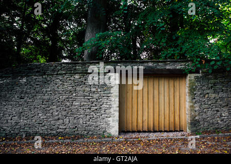Einfache Holztor in einer Steinmauer wie ein Garagentor am Eingang eine private Porperty in den Wäldern. Stockfoto