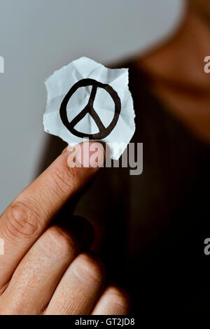 Nahaufnahme eines jungen Mannes zeigt ein Stück Papier mit ein Friedenssymbol es angesaugt Stockfoto