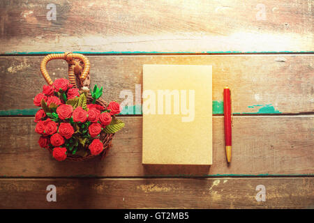 Buch und Blume in Vase auf einem Holztisch. Stockfoto