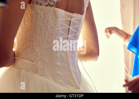 Closeup getönten Foto der schönen Braut ihr Brautkleid zu binden Stockfoto