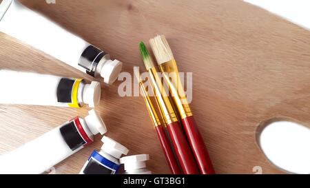 Pinsel und Acrylfarbtuben auf einer Holzpalette Stockfoto