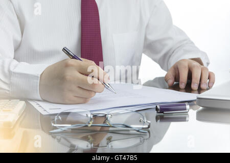 Geschäftsmann, arbeiten mit Dokumenten auf Schreibtisch mit Laptop-Computer, Taschenrechner und Gläser. Stockfoto