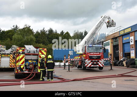 Devon, UK. 9. September 2016. Tiverton Feuer: Die Szene von einem Großbrand in den Räumlichkeiten des Warren Hughes Möbelhersteller in Ormidale Square, Tiverton Business Park, Devon, am 16.00 BST auf Freitag, 9. September 2016. Die Feuerwehr wurden bei 11,23 genannt. Fünf Stunden waren später mindestens 6 Feuerlöschfahrzeuge noch am Tatort, darunter zwei Hebebühnen. Personal in den benachbarten Einheiten wurden auch unter anderem die Räumlichkeiten der North Devon Reifen und nationalen Reifen & Autocare evakuiert. Bildnachweis: Tim Squires/Alamy Live-Nachrichten Stockfoto